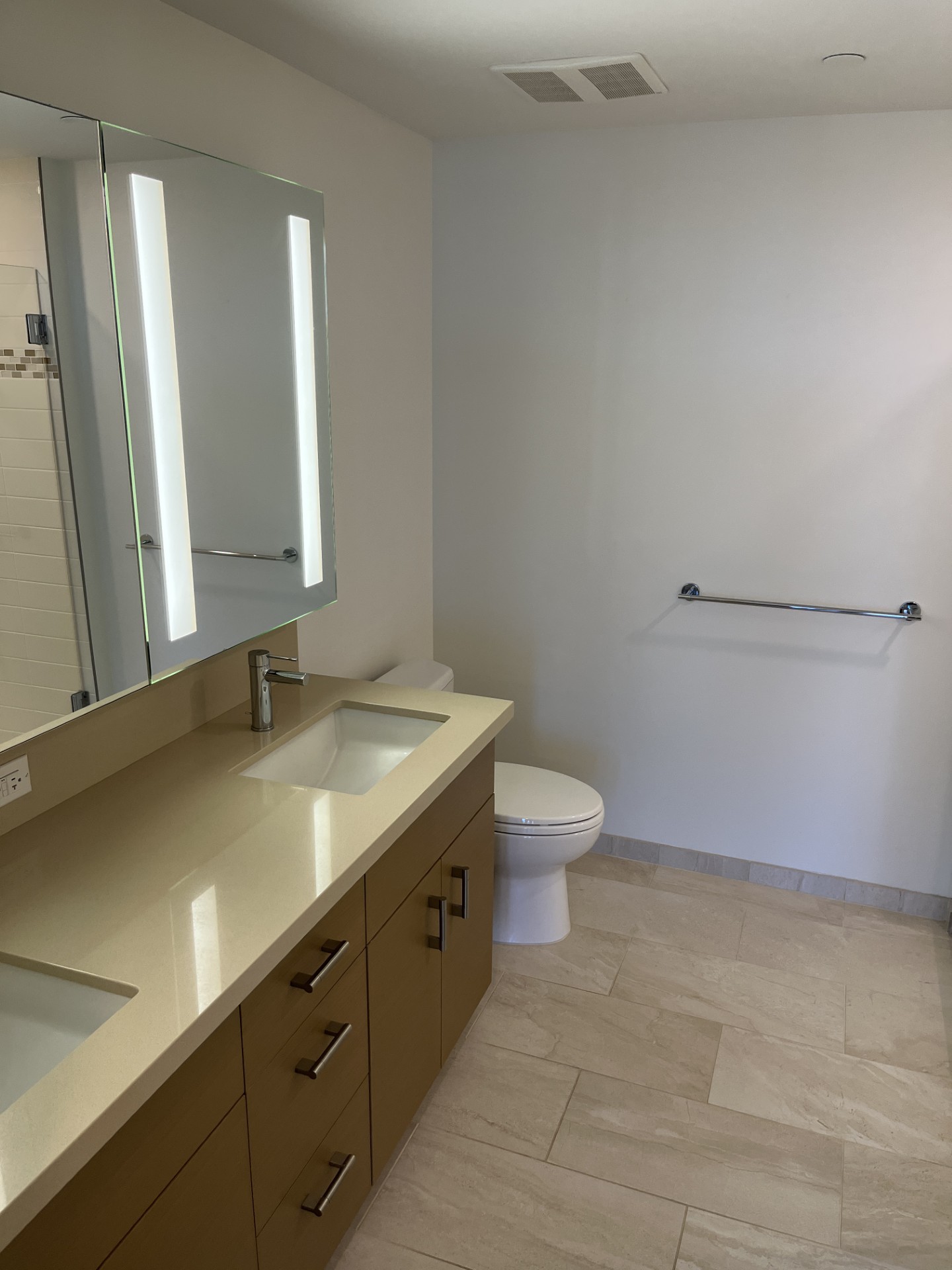 A white toilet sits in a bathroom with a sink and mirror.